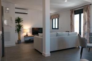 ein Wohnzimmer mit einem Sofa und einem TV in der Unterkunft APARTAMENTOS VIRGEN DEL CARMEN in El Rompido
