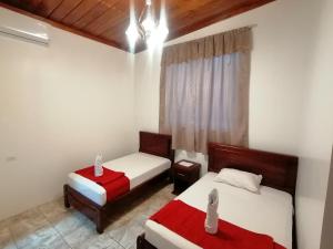 1 dormitorio con 2 camas con sábanas rojas y blancas en El Arco de Darwin, en Puerto Ayora