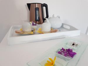 uma prateleira branca com um conjunto de chá e flores sobre ele em La Minoterie - Studio avec kitchenette et Chambre d'hôtes em Le Palais
