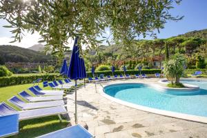 - une piscine avec des chaises longues et des parasols bleus dans l'établissement Bilocale Sant'Anna Vicolo del Mughetto, à SantʼAnna