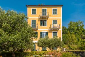 a yellow building with two balconies and trees at Pensieri Marini, TerreMarine in Corniglia