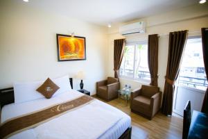 a hotel room with a bed and two chairs at Canary Boutique Hotel in Hue