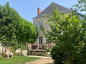 an old gray house with a balcony in the yard at Agréable maison de bourg aux portes de TOURS in Semblançay