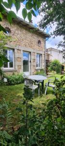 a picnic table and bench in front of a stone house at Bienvenue aux Lavandières. in Montrollet