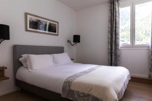 Schlafzimmer mit einem Bett mit weißer Bettwäsche und einem Fenster in der Unterkunft Le Majestic 145 Appt - Chamonix All Year in Chamonix-Mont-Blanc