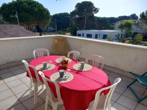 a table with a red table cloth on a balcony at Les Cyclades, T3 climatisé, terrasse, 500m plage in Le Grau-dʼAgde