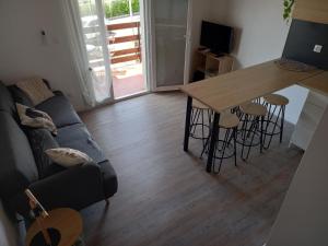 a living room with a couch and a table with stools at Les Cyclades, T3 climatisé, terrasse, 500m plage in Le Grau-dʼAgde