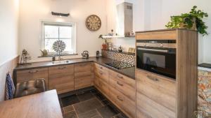 a kitchen with wooden cabinets and a sink at B&B Zilverstad Huisje De Veerpoort in Schoonhoven