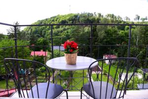 a table with a vase of flowers on a balcony at Apartamenty Turystyczna 25 blisko centrum, z dodatkowym bezpłatnym parkingiem w centrum miasta in Kudowa-Zdrój