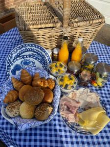 una mesa con platos de comida y una cesta de zumo de naranja en B&B Zilverstad Huisje De Veerpoort, en Schoonhoven