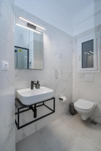アテネにあるSunny And Cozy 2bd Apt 1 min from Marina Floisvosの洗面台とトイレを備えた白いバスルーム