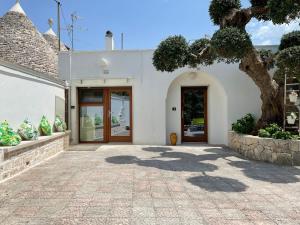 a white building with a door and a tree at Il trullo di nonno Licchio in Alberobello