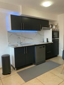 a kitchen with black cabinets and a sink at Le Venise 3 Etoiles Frejus in Saint-Aygulf