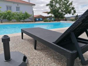 a black bench sitting next to a swimming pool at Casa das Indrineiras in Mogadouro