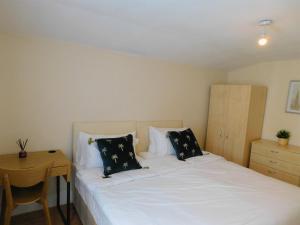 um quarto com uma cama branca e uma mesa de madeira em Entire 4 bedroom Terrace house in London em Londres