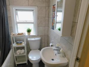 uma casa de banho com um WC, um lavatório e uma janela em Entire 4 bedroom Terrace house in London em Londres