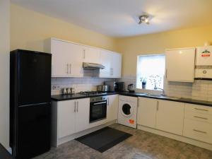 a kitchen with white cabinets and a black refrigerator at Entire 4 bedroom Terrace house in London in London