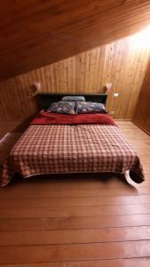 Cama en habitación con pared de madera en Cozy family apartment for rest and fun, en Sella Nevea