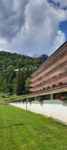 a large building with a grass field in front of it at Cozy family apartment for rest and fun in Sella Nevea