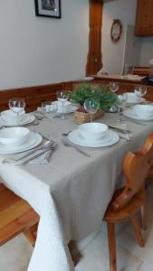 a table with white plates and wine glasses on it at Cozy family apartment for rest and fun in Sella Nevea