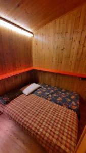 Cama pequeña en habitación con paredes de madera en Cozy family apartment for rest and fun, en Sella Nevea