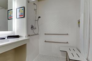 a white bathroom with a shower and a sink at Holiday Inn Mobile Airport, an IHG Hotel in Mobile