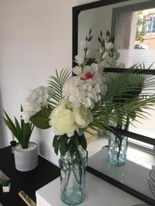 twee vazen met bloemen op een tafel voor een spiegel bij Chambre privée face à la gare in Tarbes