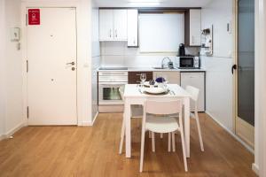 a white kitchen with a white table and chairs at Apartamento Buen Camino in Benidorm
