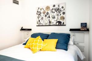 a bed with yellow and blue pillows on it at Apartamento Buen Camino in Benidorm