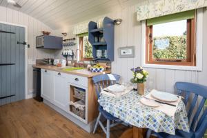 una pequeña cocina con mesa, mesa y sillas en Teasel Shepherd's Hut, en Berwick-Upon-Tweed