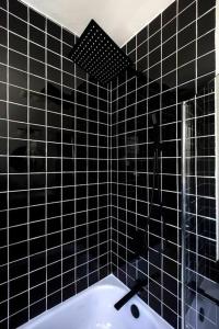 a black tiled bathroom with a tub and a shower at Artist's Retreat In The Woods Five Acre Backyard in Roxbury