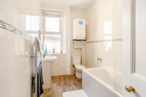 a white bathroom with a tub and a toilet at The Retreat in Wigton