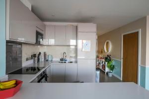 a kitchen with white cabinets and a counter top at Amazing London City Skyline View & Transport Links in Barking