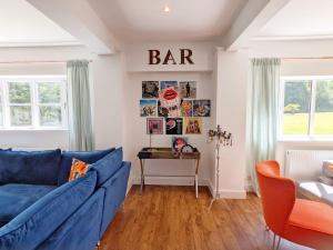 a living room with a blue couch and a bar on the wall at Priory Coach House - Church Norton in Selsey