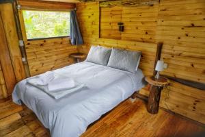 ein Schlafzimmer mit einem Bett in einem Blockhaus in der Unterkunft Habitación Colibrí, Pijao, Finca Flora del Río in Pijao