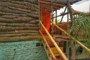 une maison en bois avec une porte rouge et des escaliers dans l'établissement Habitación Colibrí, Pijao, Finca Flora del Río, à Pijao