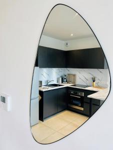 un miroir reflétant une cuisine avec des placards noirs dans l'établissement NB ARROWS Appartement de standing en hyper centre, à Chartres