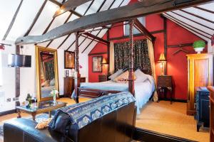 Finest Retreats - The Hayloft at Greystones في Swinderby: غرفة نوم بسرير مظلة وجدران حمراء