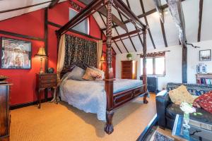 a bedroom with a canopy bed and red walls at Finest Retreats - The Hayloft at Greystones in Swinderby