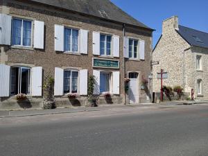 um edifício de tijolos com persianas brancas numa rua em Chambres d'hôtes les Clématites en Cotentin em Saint-Floxel