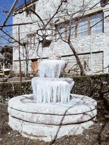 a snow covered fountain in front of a building at Lodges VEIS in Kamenicë