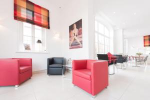 a waiting room with red chairs and tables at Hotel Am Burgmannshof in Wunstorf