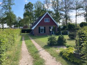 a red house with a dirt road in front of it at Het Kottens Huisje in Kotten