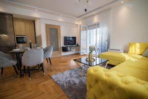 a living room with a yellow couch and a dining room at July in Trebinje