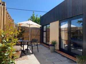 a patio with an umbrella and a table and chairs at The Burrow at Tankerton in Whitstable