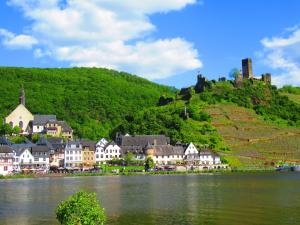 a town on a hill next to a body of water at Ferienhaus Leopold mit Burgblick an der Mosel in Burgen