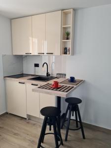 a kitchen with white cabinets and two bar stools at Apartmani Donata in Rijeka