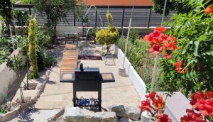 a patio with a grill in a garden with flowers at Apartment Alena with terrace and garden Center Jelsa in Jelsa