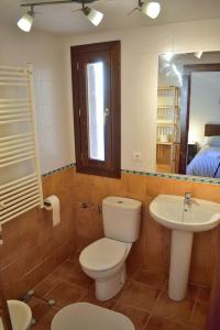 y baño con aseo, lavabo y espejo. en Casa El Parral 2 dormitorios en Santa Cruz de la Serós