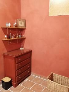 una camera con una parete rossa e un comò in legno di Maison renovee en pierres séjour spacieux avec jardin et terrasse aménagée près Omaha beach & Bayeux à 5mn de la mer tous commerces a Commes Altre 38 foto